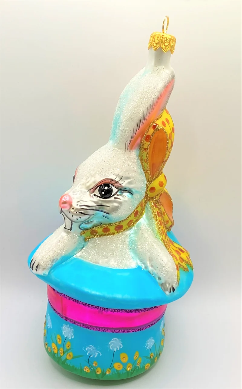 Weisser Osterhase sitzt im bunten Frühlings - Hut