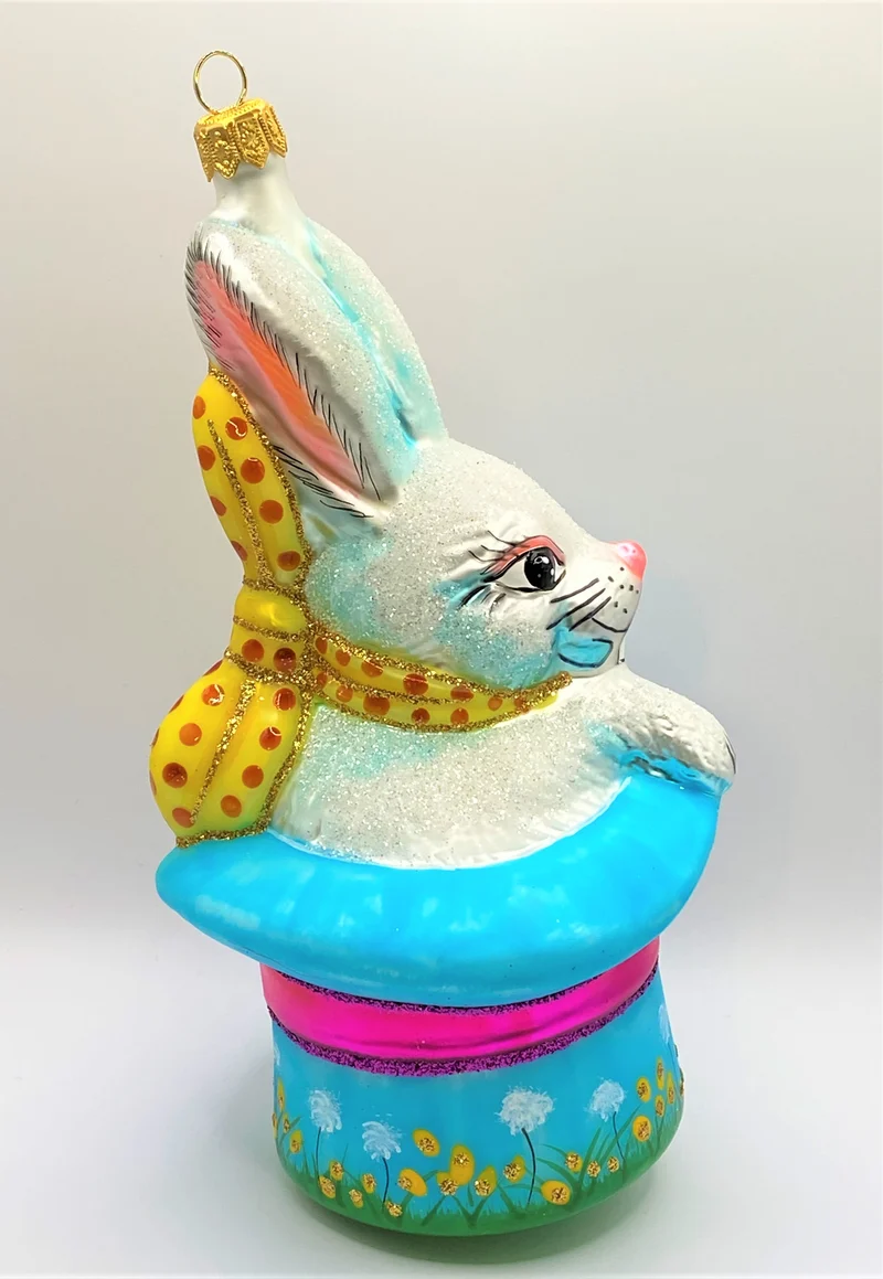 Weisser Osterhase sitzt im bunten Frühlings - Hut