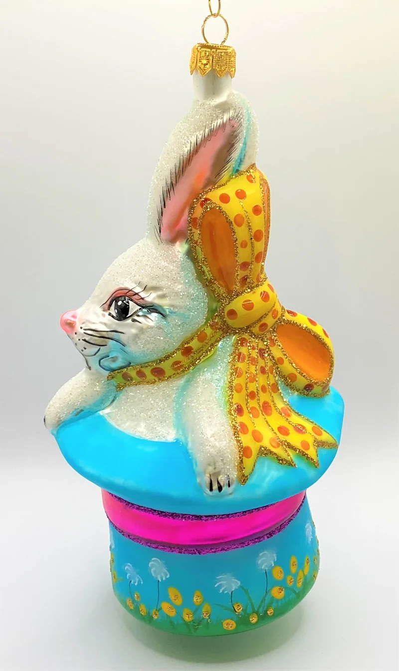 Weisser Osterhase sitzt im bunten Frühlings - Hut