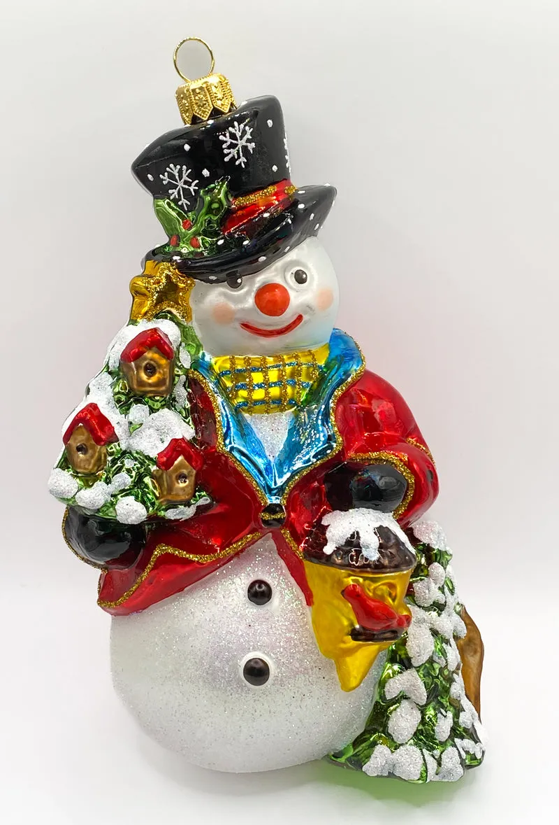 Schneemann bringt den Weihnachtsbaum geschmückt mit Vogelhäuschen