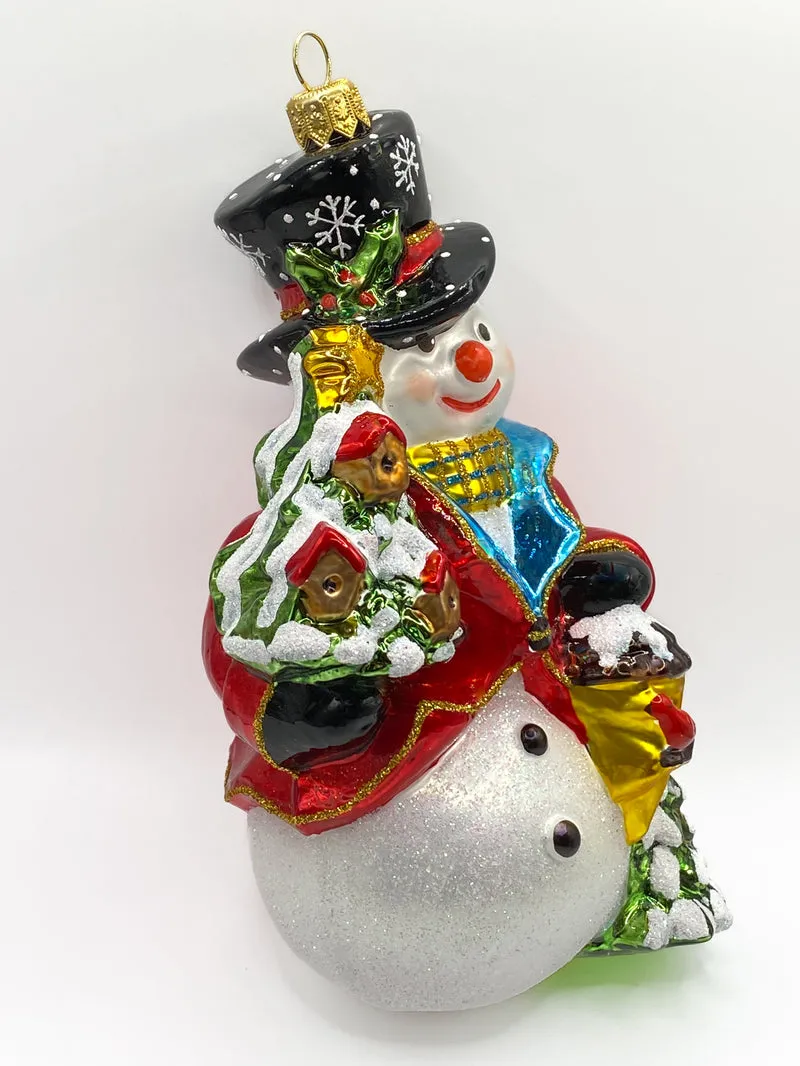 Schneemann bringt den Weihnachtsbaum geschmückt mit Vogelhäuschen
