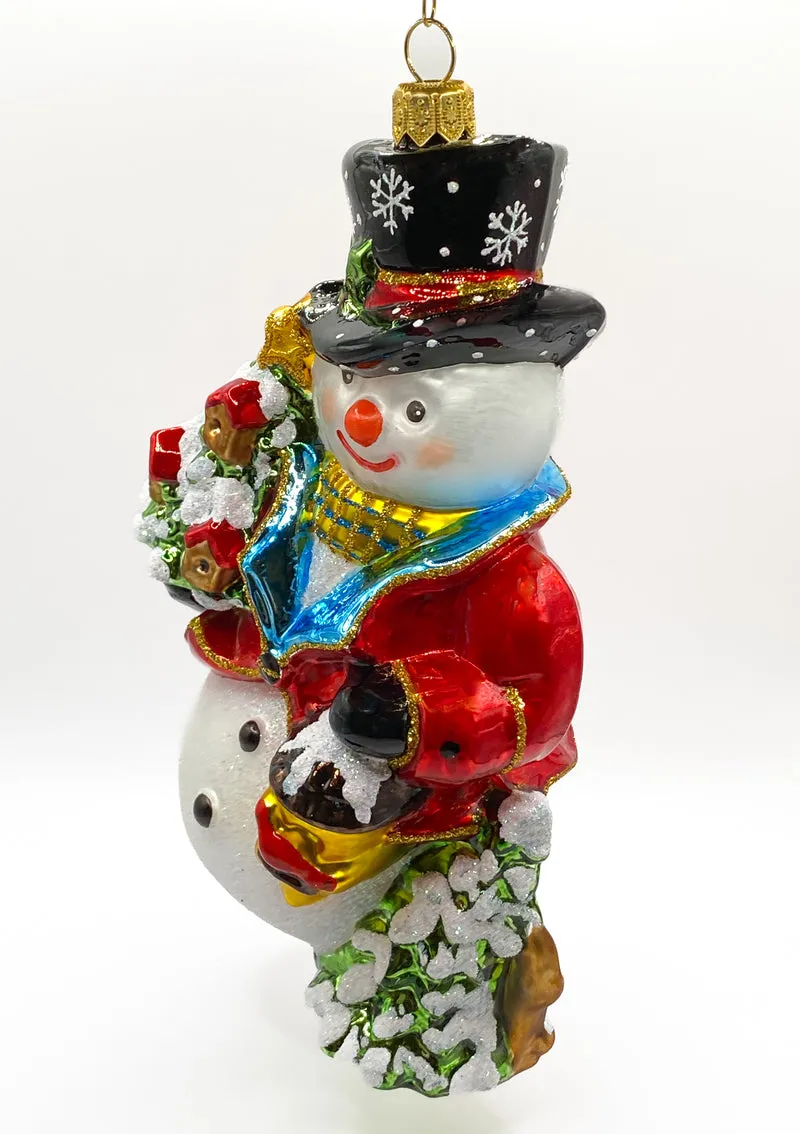 Schneemann bringt den Weihnachtsbaum geschmückt mit Vogelhäuschen