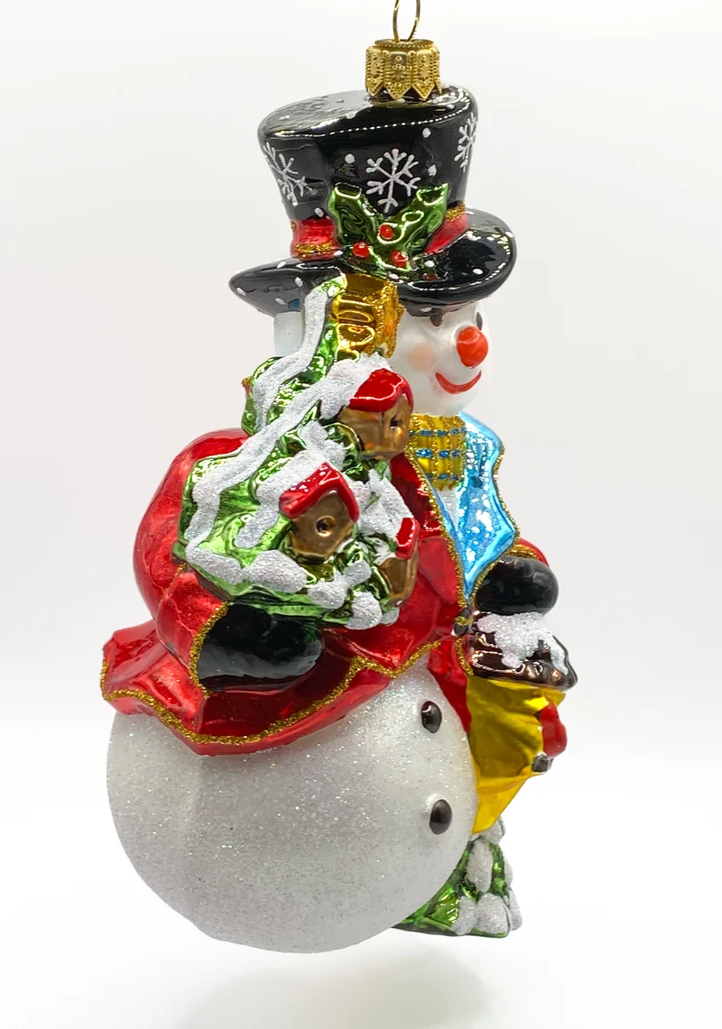 Schneemann bringt den Weihnachtsbaum geschmückt mit Vogelhäuschen