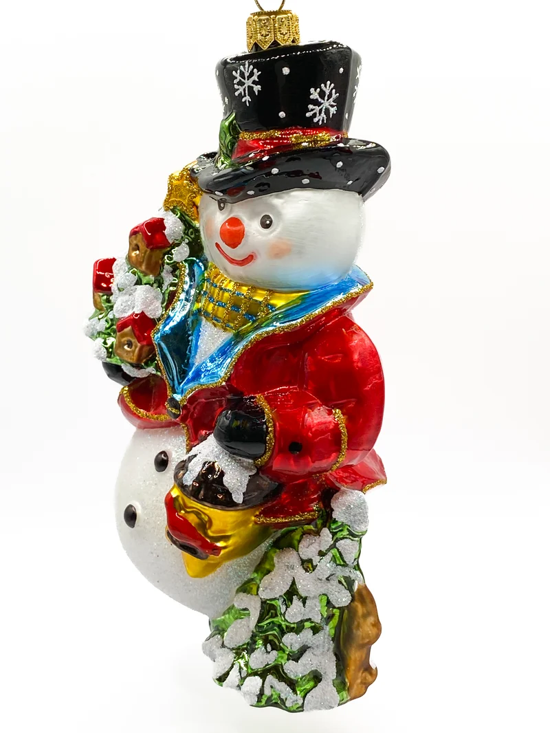 Schneemann bringt den Weihnachtsbaum geschmückt mit Vogelhäuschen