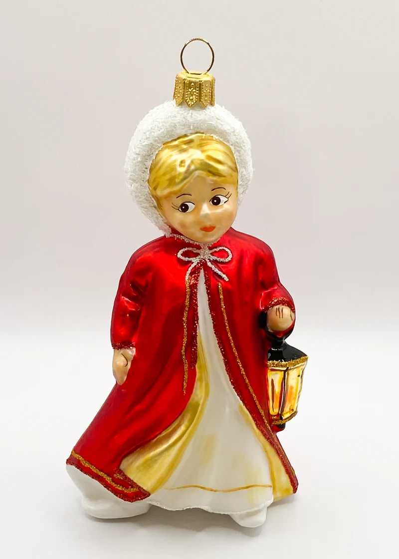 Das Christkind im roten Cape leuchtet mit der Laterne