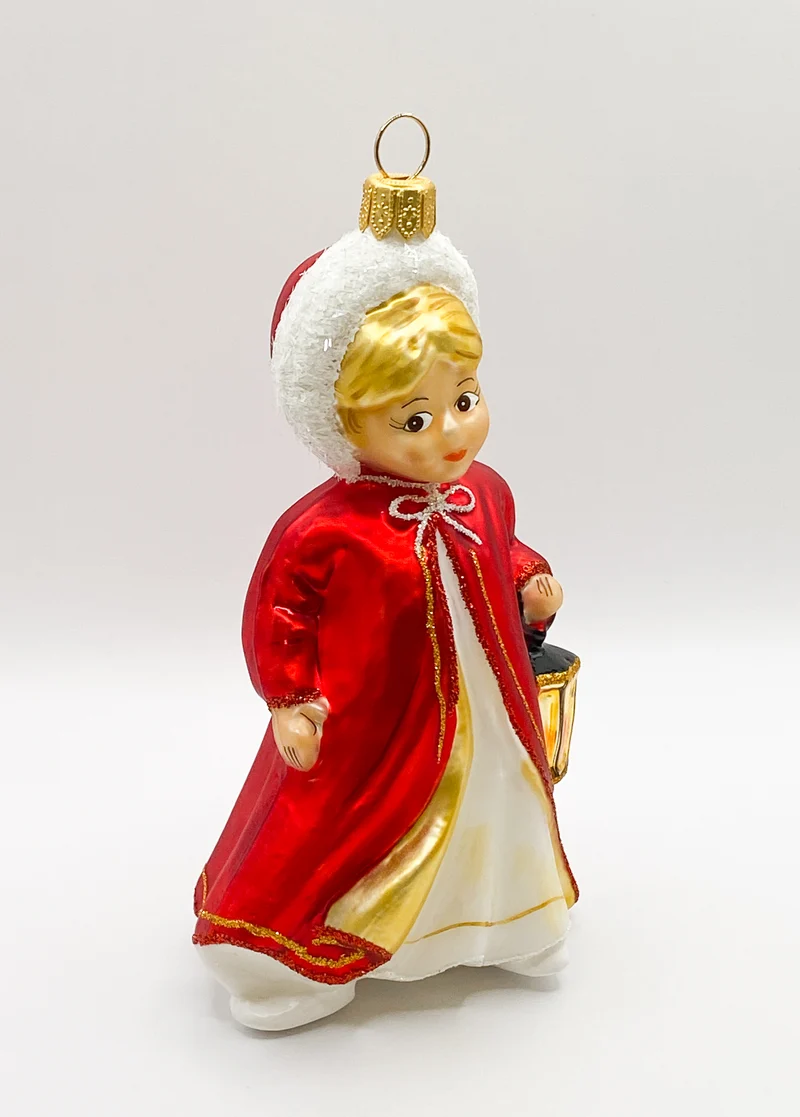 Das Christkind im roten Cape leuchtet mit der Laterne