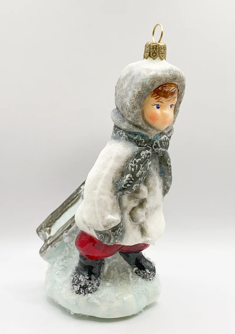 Der kleine Junge stapft mit dem Schlitten durch den Schnee, AtlasArt