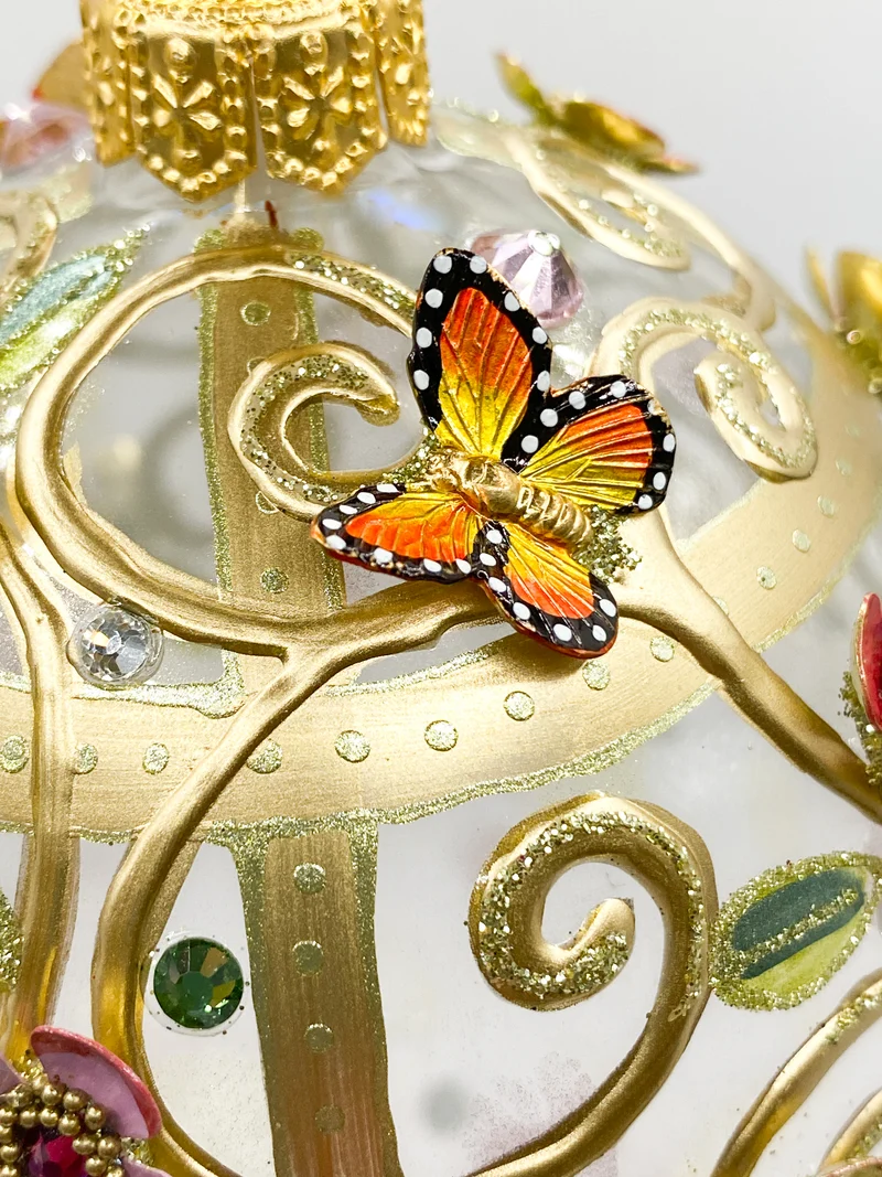 Eiform mit strukturiert gemaltem Ranken-Dekor und metallenen Blüten und Schmetterling Applikationen,