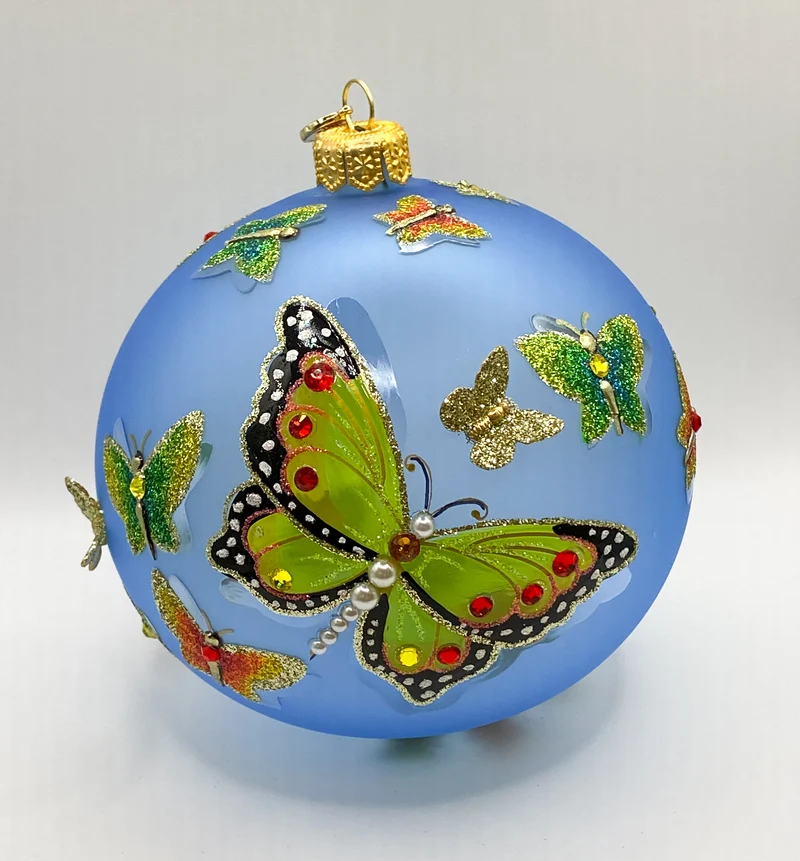 Transparente hellblaue Kugel mit strukturiert gemalten Schmetterlingen und metallenen Schmetterling