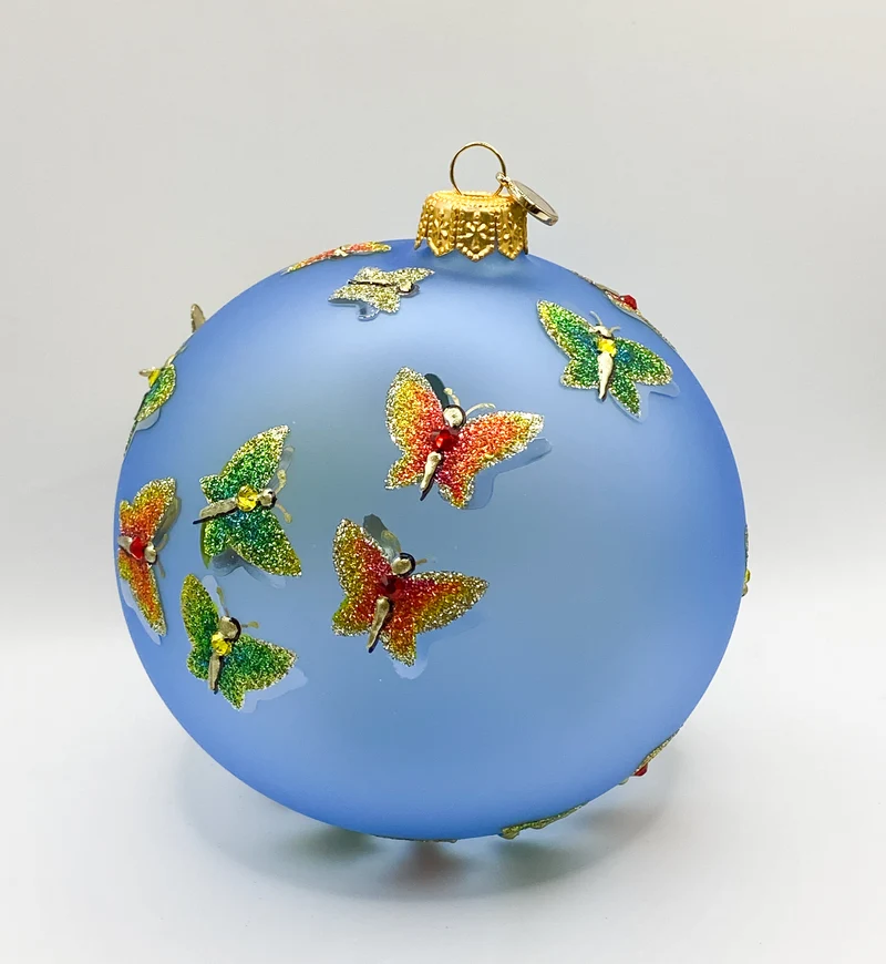 Transparente hellblaue Kugel mit strukturiert gemalten Schmetterlingen und metallenen Schmetterling