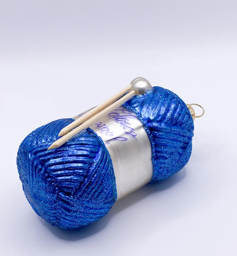 Blauer Wollknäuel mit Stricknadeln