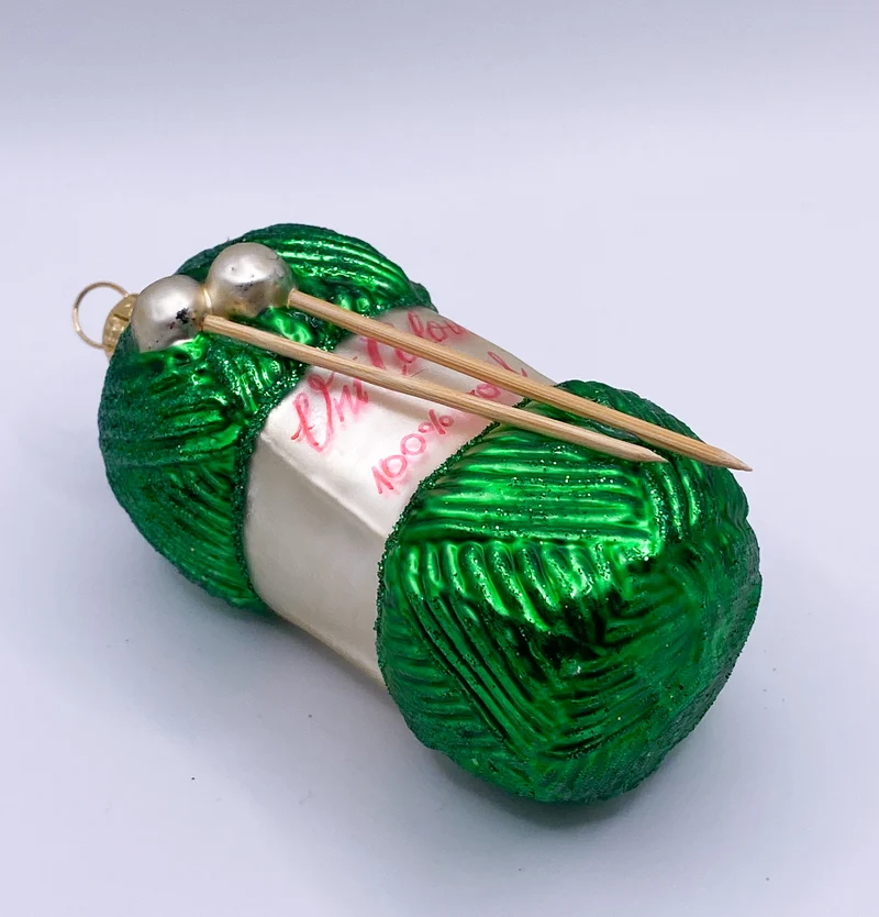 Grüner Wollknäuel mit Stricknadeln