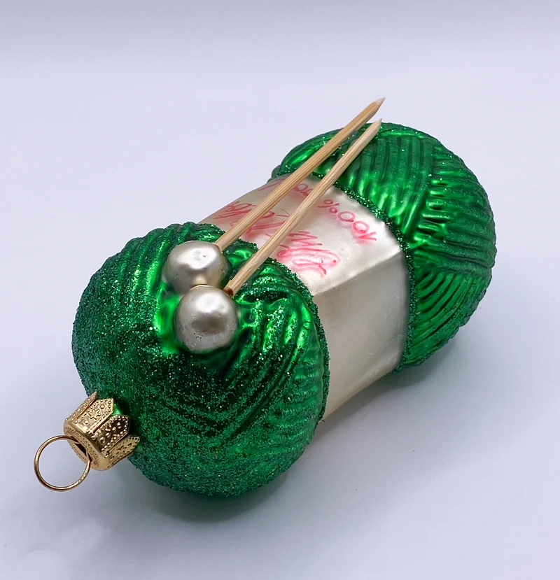 Grüner Wollknäuel mit Stricknadeln